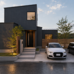 Modern two‑story dark gray house with a small front yard, lit entry, and a white sedan plus a black SUV in the driveway