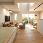 Bright open-concept living space with tatami seating, low coffee table, TV, and sliding doors to a sunny garden.
