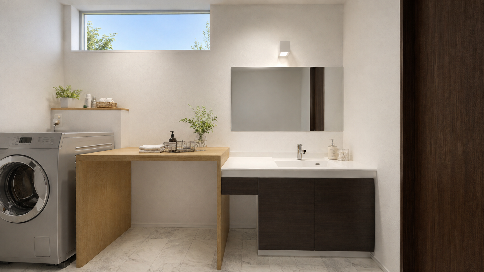 Laundry room with front-load washer, wood counter, and white sink beneath a large mirror; plants on the counter and a high horizontal window above.