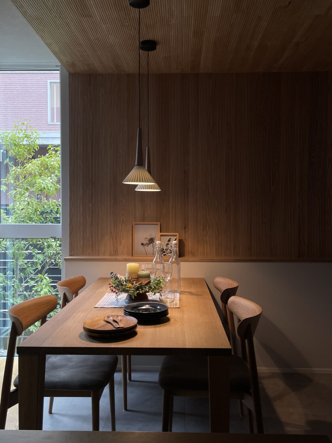 Wood-paneled dining room with a long table set for a meal beneath pendant lights.